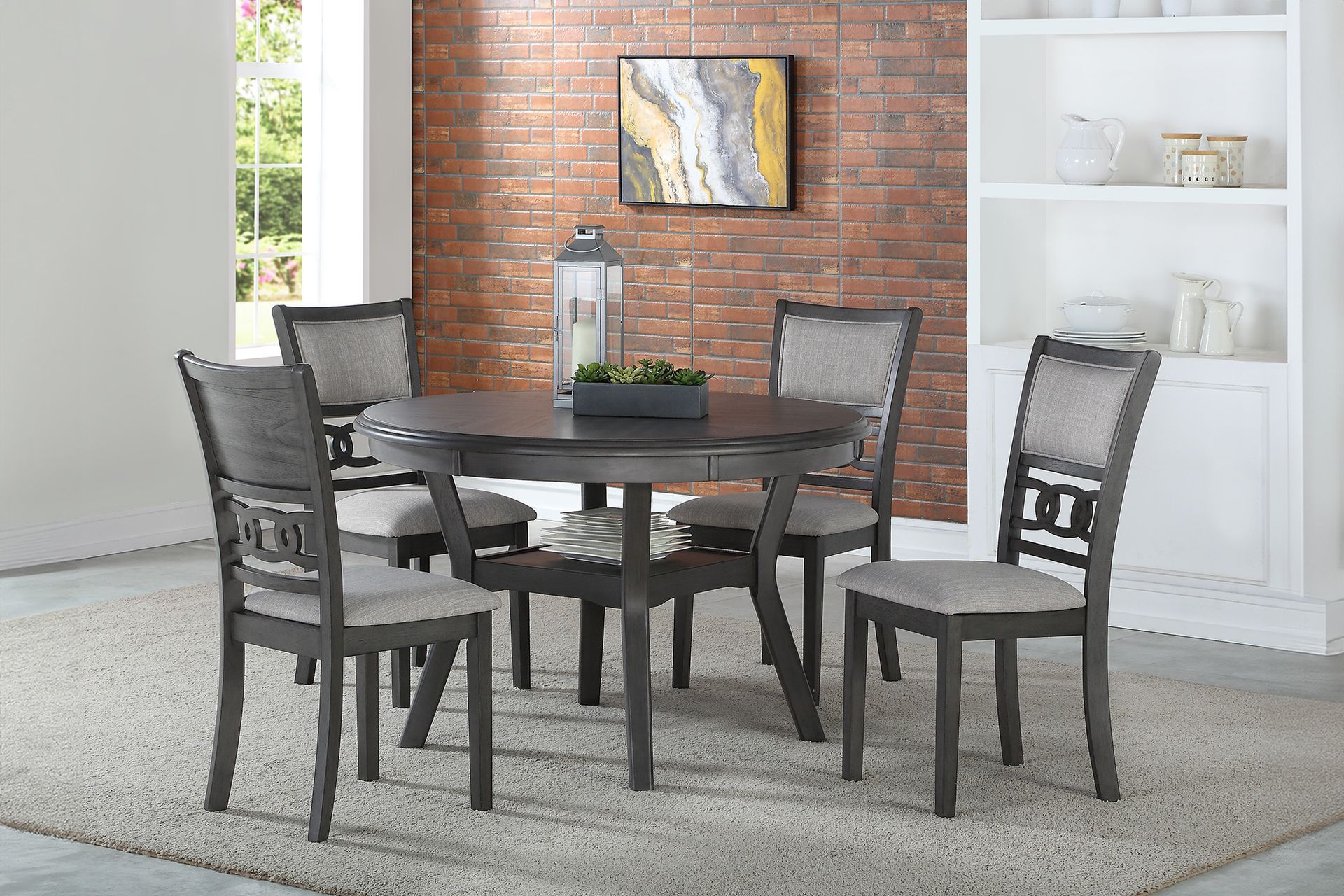 Dark wooden dining table with four chairs in a bright room with brick accent wall and white shelves