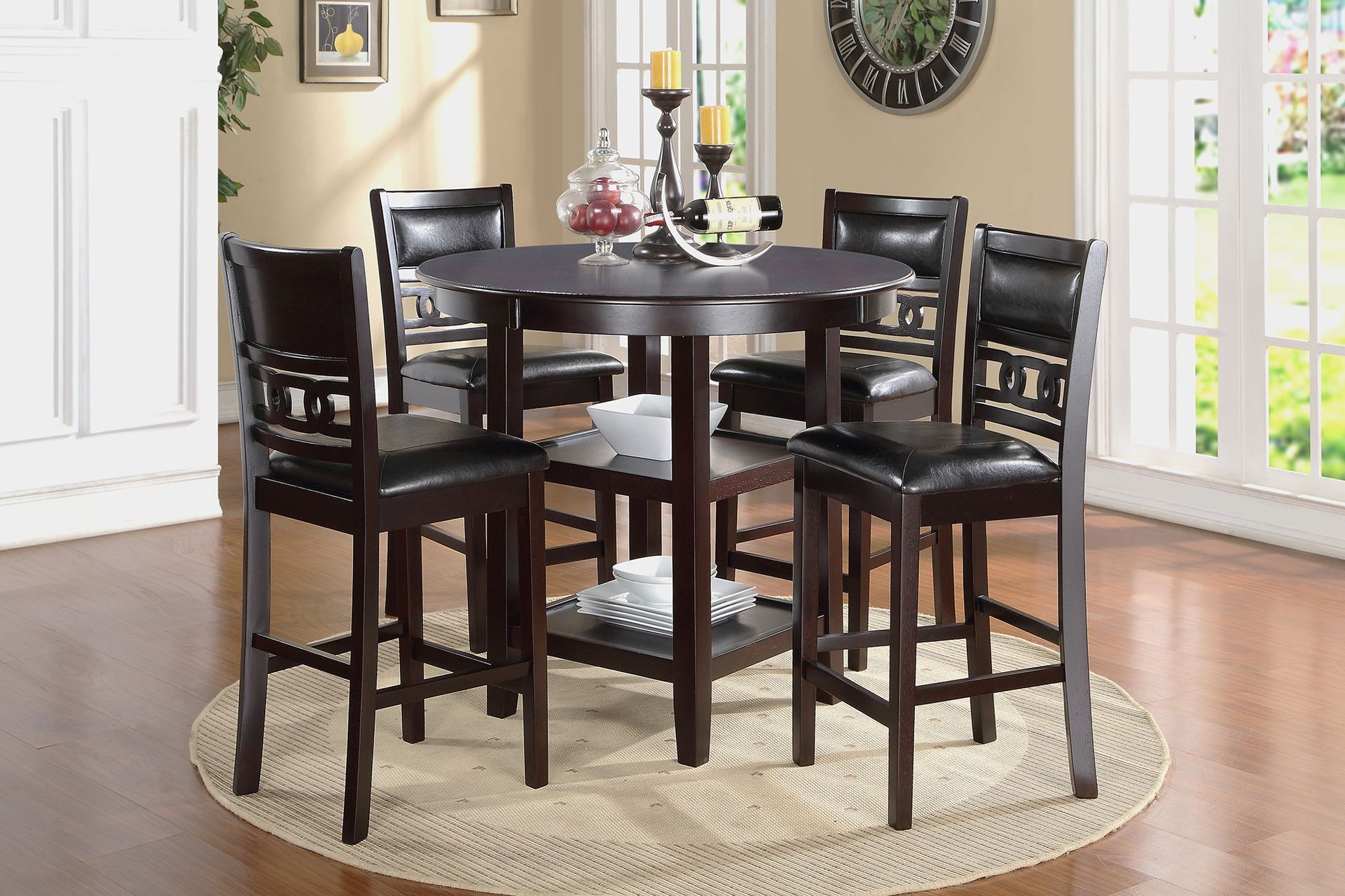 Round dark wood dining table with four chairs on a beige rug in a bright dining room
