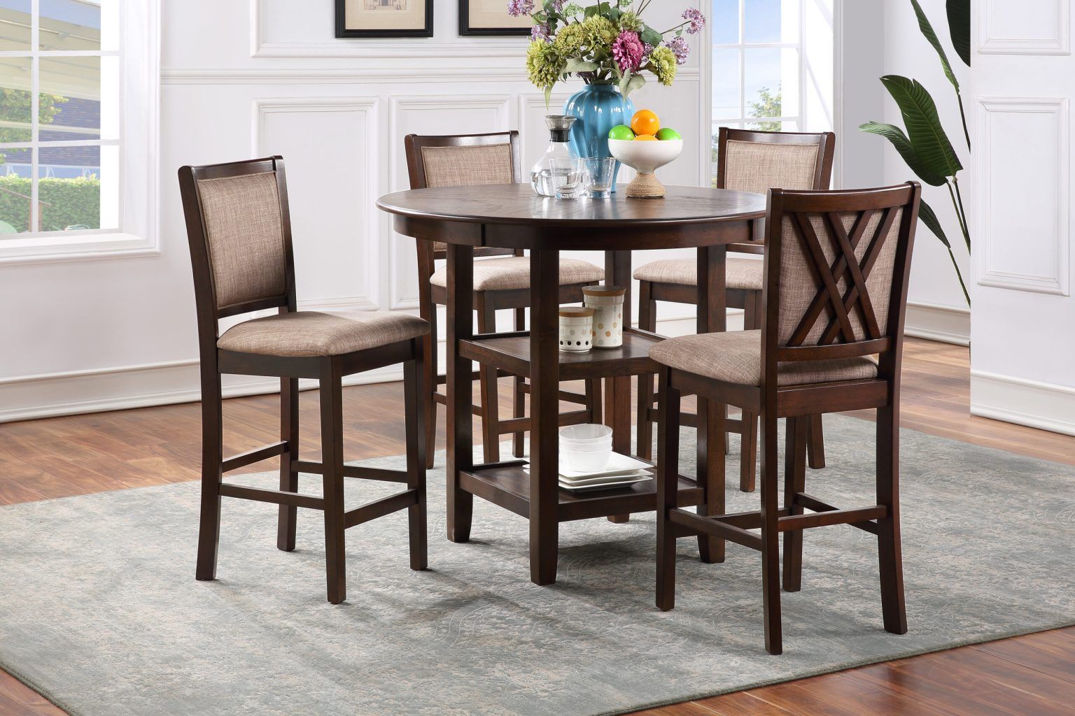 Wood dining table with four chairs and a blue floral centerpiece in a bright dining room