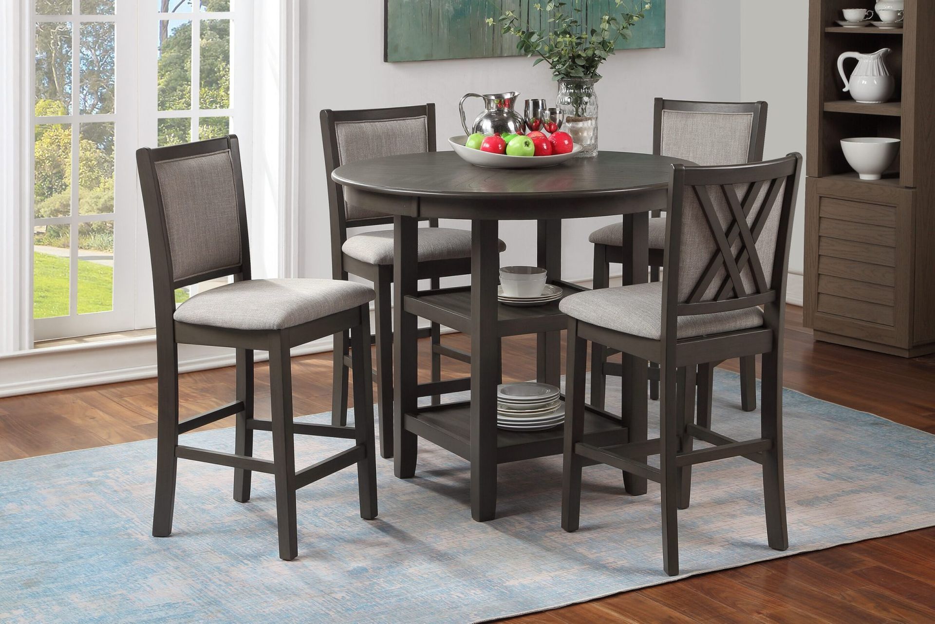 Round dining table with four chairs on a light rug in a bright room by a window