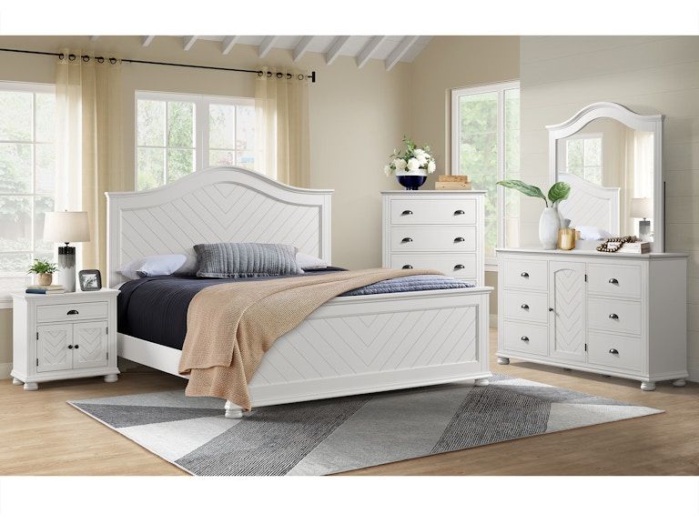 Bright white bedroom set with upholstered bed, dressers, mirror, and gray rug in a sunlit room