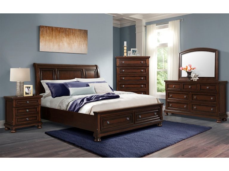 Bedroom set with dark wood bed, dresser, nightstands, mirror, and blue rug in a bright room