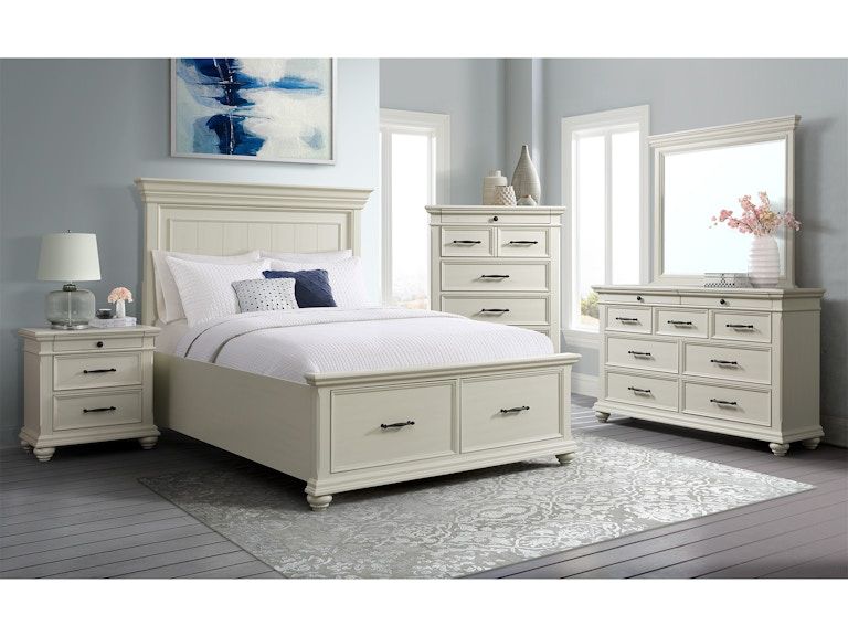 Bright bedroom set with white upholstered bed, dresser, nightstand, chest, mirror, and blue wall art