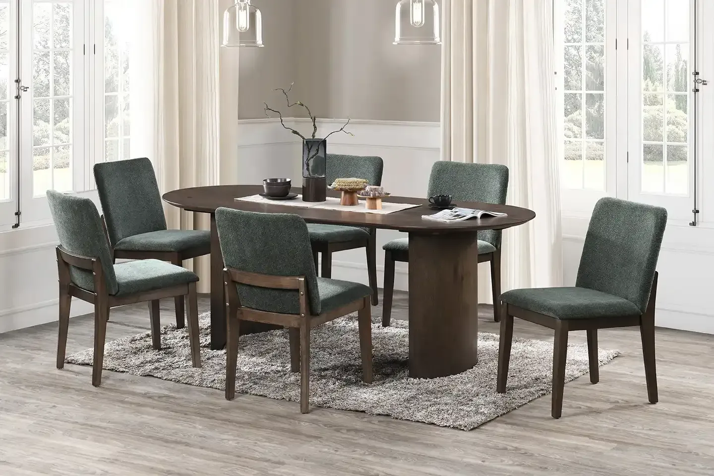 Dark wood dining table with four green upholstered chairs in a bright dining room