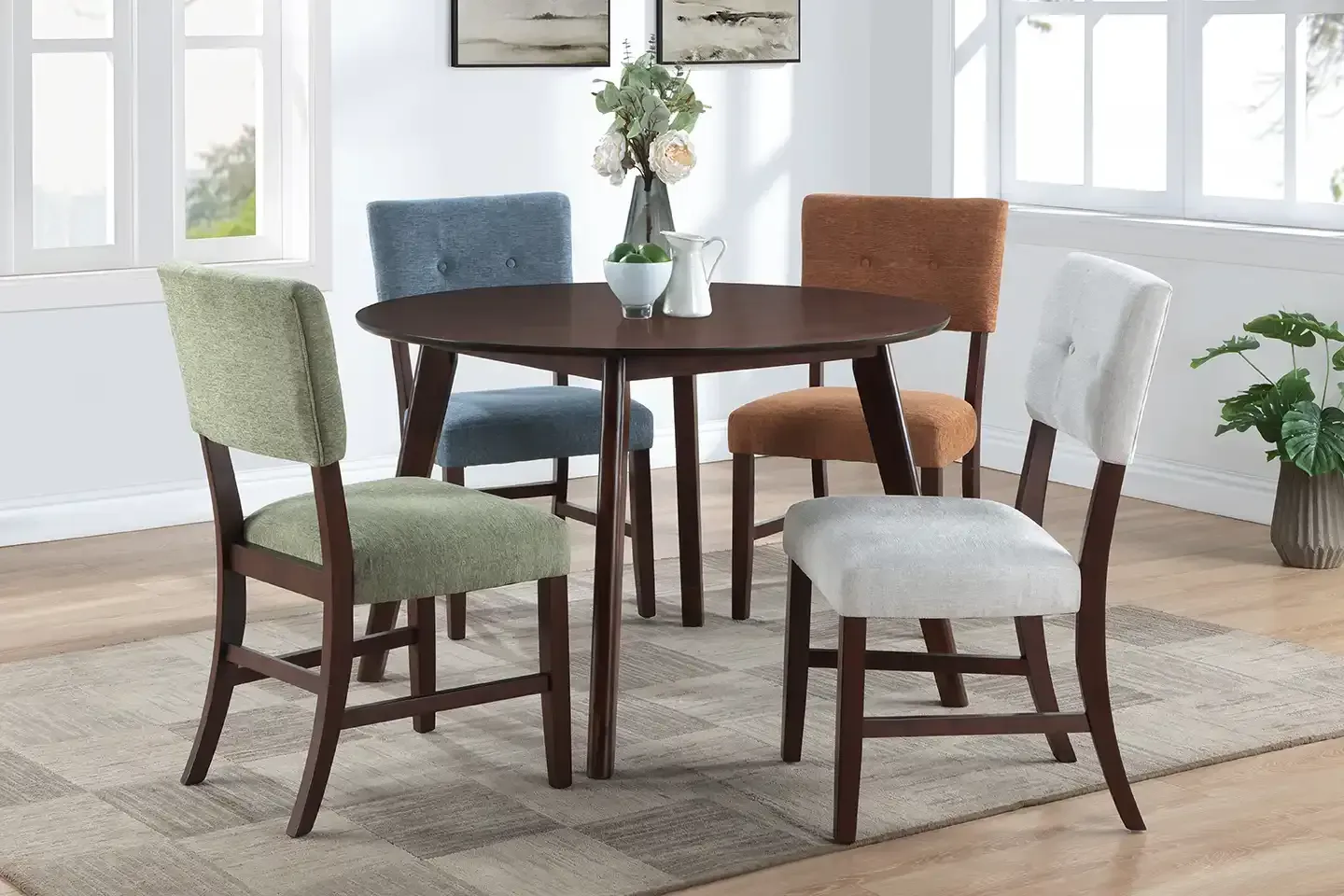 Dining table with four upholstered chairs in a bright room with windows and a rug
