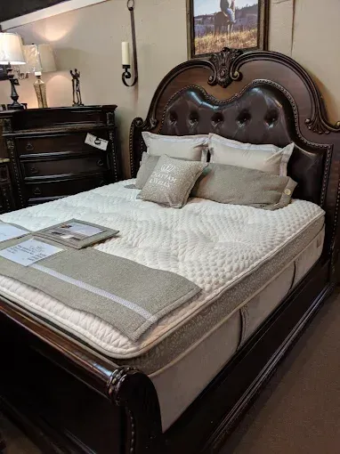 Elegant bedroom with a dark wood bed, beige bedding, and a dresser beside it