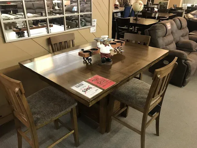 Dining room with wooden table and chairs, centered decor, and a couch in the background.