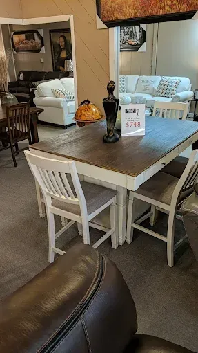 Cozy furniture showroom with dining table, white chairs, and sofas in the background