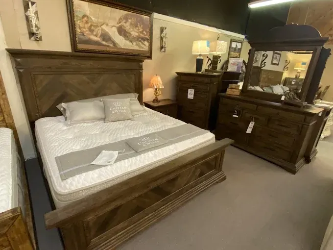 Wooden bedroom set with bed, dresser, mirror, and nightstand in a furniture showroom