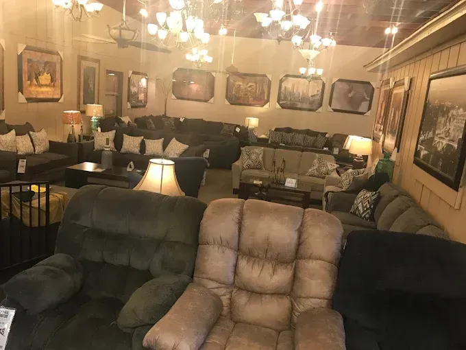 Warm living room with leather sofas, chandelier lights, framed art, and a cozy lamp-lit seating area