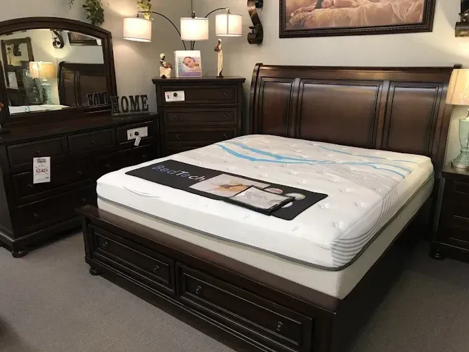 Black bedroom set with a dark wood bed, dresser, mirror, and lamp.