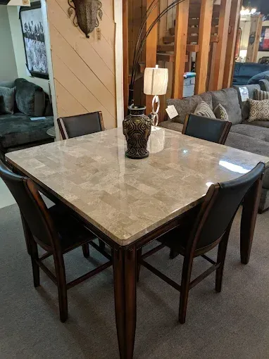 Square marble-top dining table with four dark chairs in a living room setting