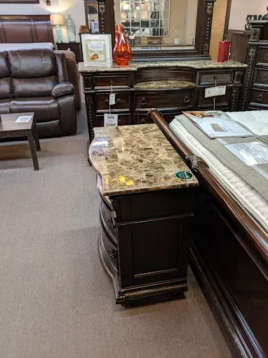 Furniture showroom with dark wood desks, leather recliner, and decorative accents on display