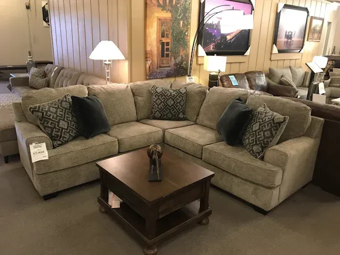 Living room with beige sectional sofa, patterned pillows, and a dark wood coffee table
