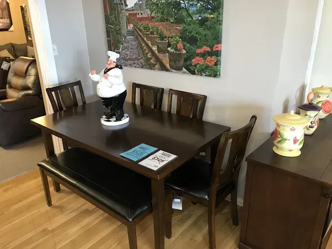 Dining room with dark wood table, bench, chairs, and a small Santa figurine centerpiece.