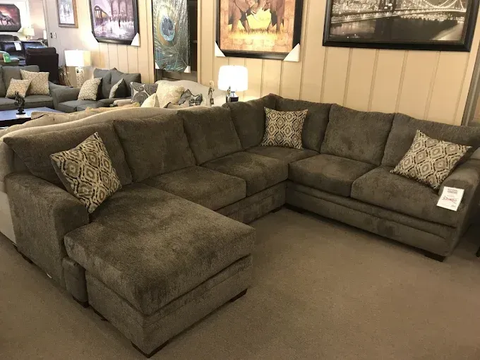 Large brown sectional sofa in a furnished living room with framed wall art and a lamp.