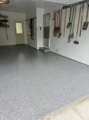 Garage with a gray speckled epoxy floor and tools hanging on the wall.