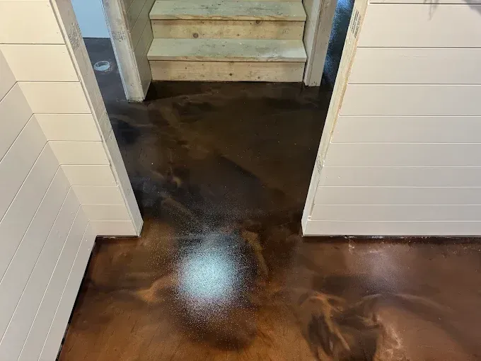 Metallic brown epoxy floor leading to a set of stairs, framed by white shiplap walls.