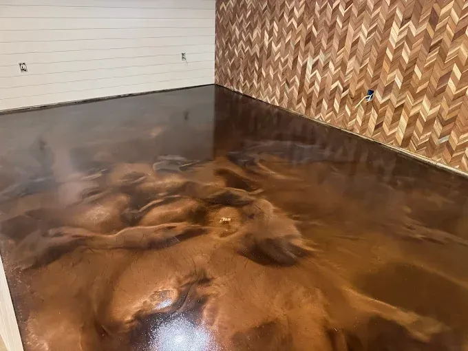 Copper-colored epoxy floor with swirling patterns in a room, adjacent to a wood chevron wall.