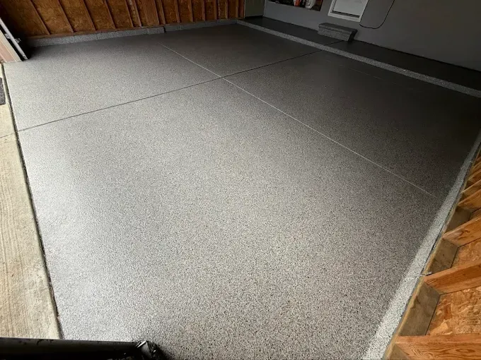 Gray epoxy-coated garage floor with speckles; light reflected.