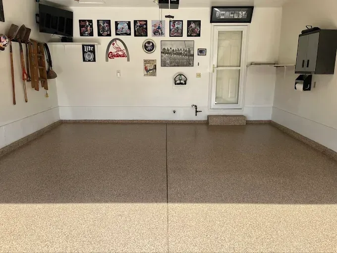 Empty garage with speckled tan floor, white walls, and various decorations.