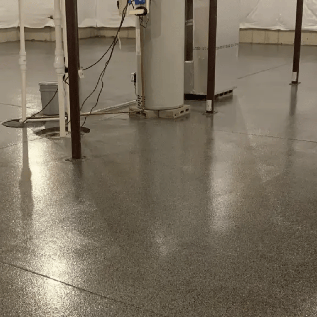 Shiny gray epoxy floor in a basement with support beams and utilities.