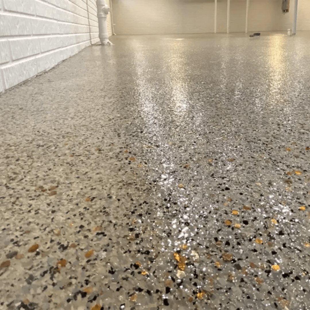 Shiny, speckled concrete garage floor. White brick wall to the left.