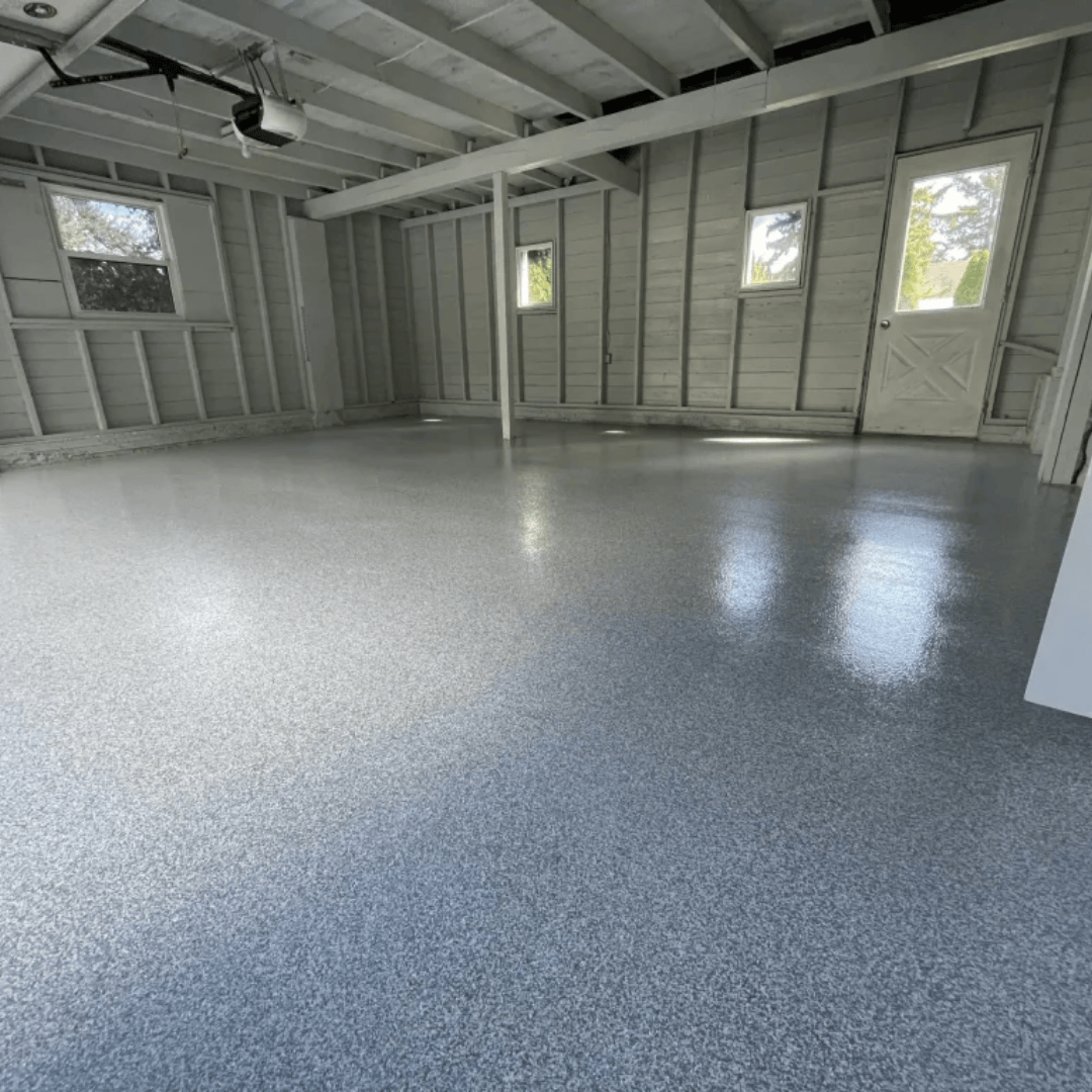 Garage interior with a shiny, speckled gray floor. White walls, windows, and door.