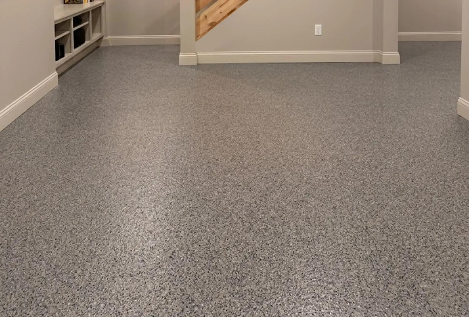 Empty modern room with grey walls, terrazzo floor, and sliding glass doors.