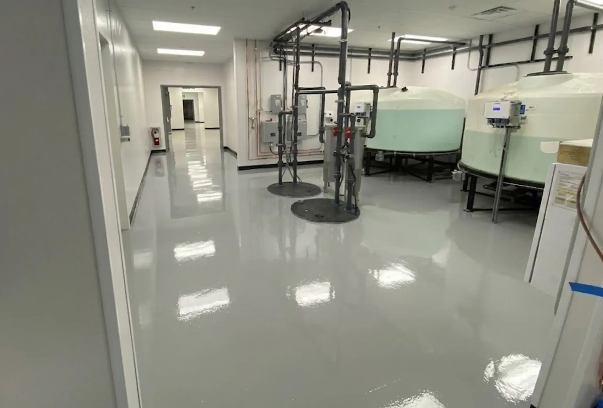 Empty, modern warehouse interior with white walls, concrete floor, and skylights.