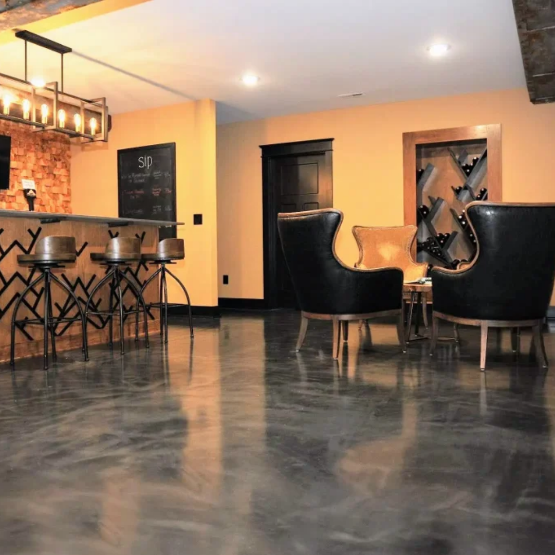 Basement with bar, chairs, and shiny flooring. Orange walls, dark furniture, and a chalkboard.