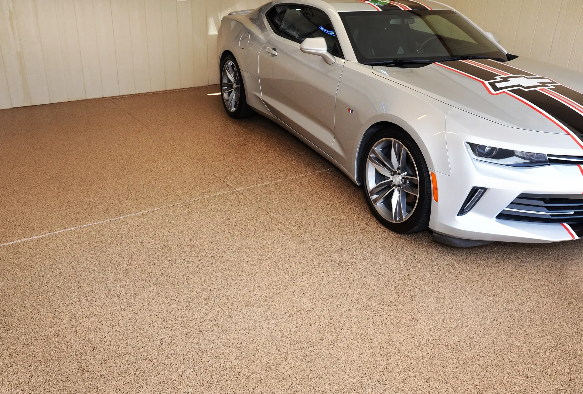 Red vintage Corvette in a garage setting with a rustic facade.