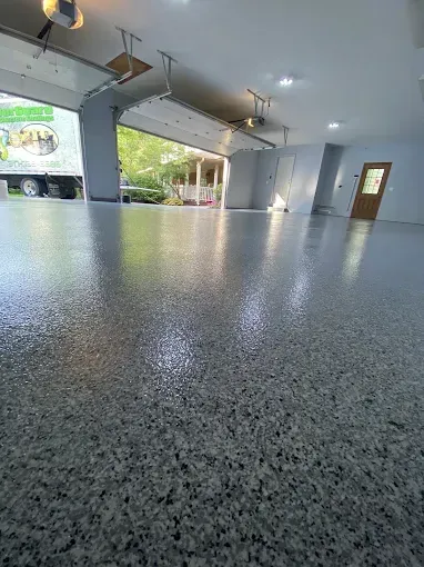 Glossy, speckled gray garage floor. Open garage door with truck visible; interior walls and door.