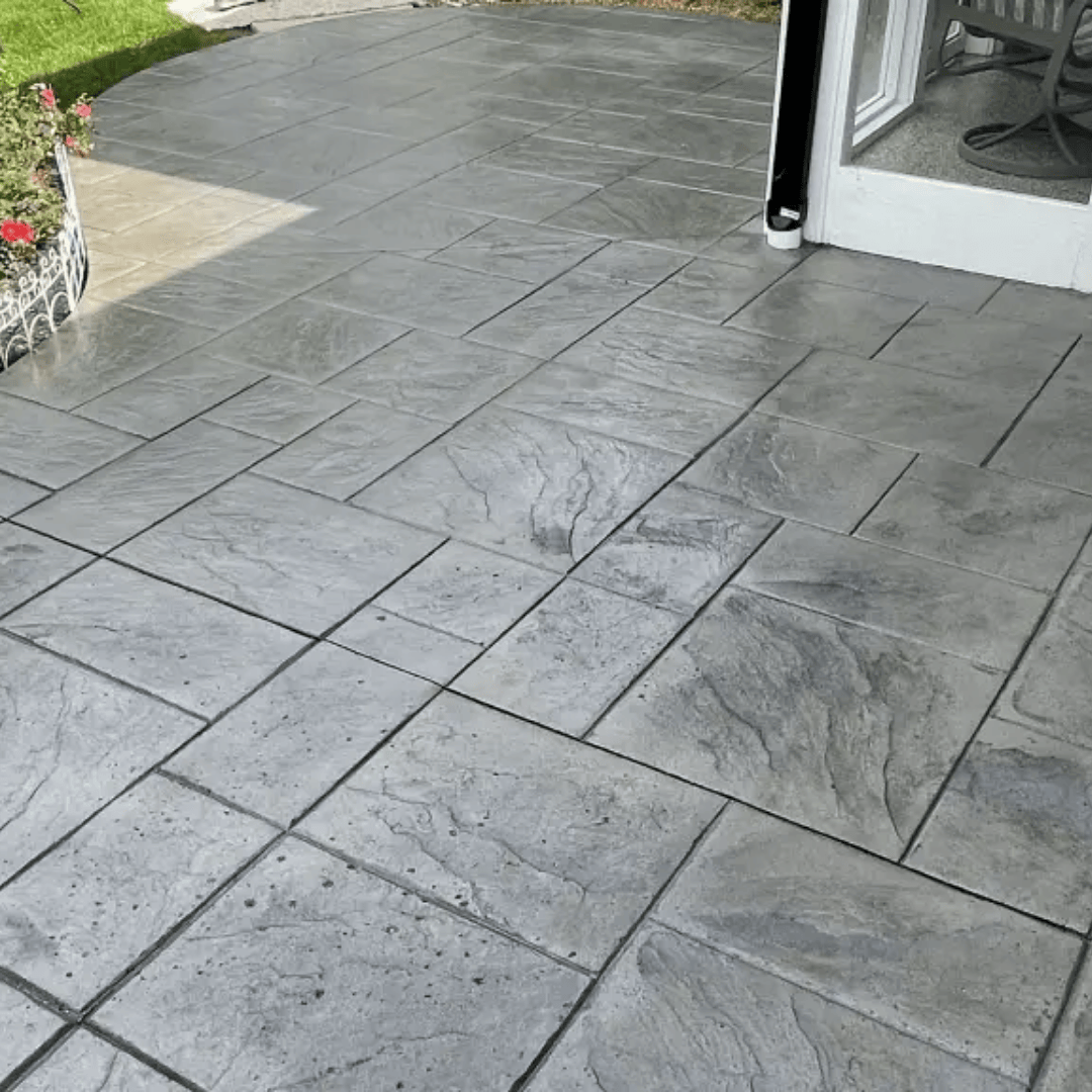 Gray, textured concrete patio with rectangular and square tile pattern.