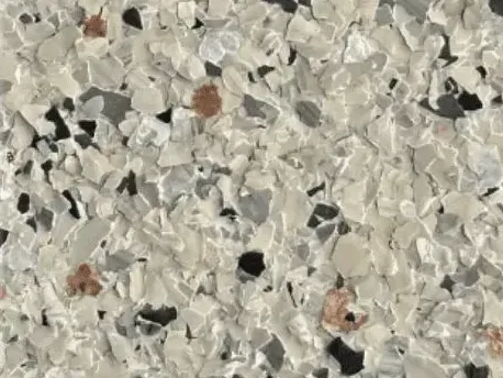 Close-up of a speckled floor coating, featuring a mix of white, gray, black, and rust-colored flakes.