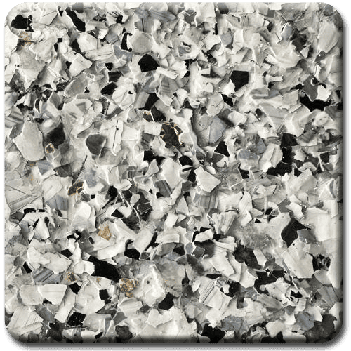 Close-up of a speckled flooring sample. Primarily white, gray, and black chips of varying sizes are visible.
