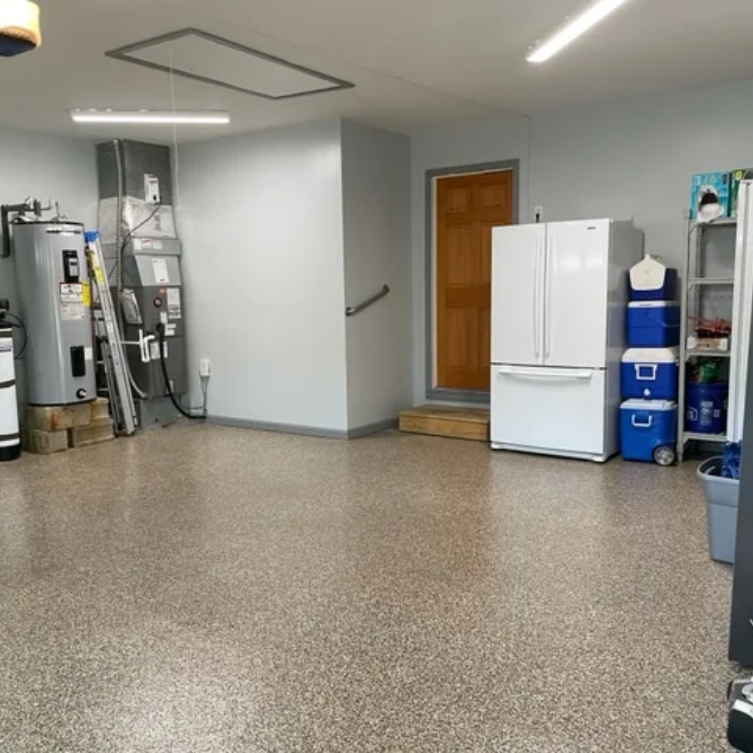 A garage interior with speckled flooring, appliances, storage, and a closed wooden door.