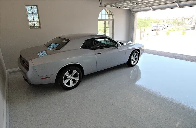 Silver Dodge Challenger parked inside a garage with a glossy, light-colored floor.