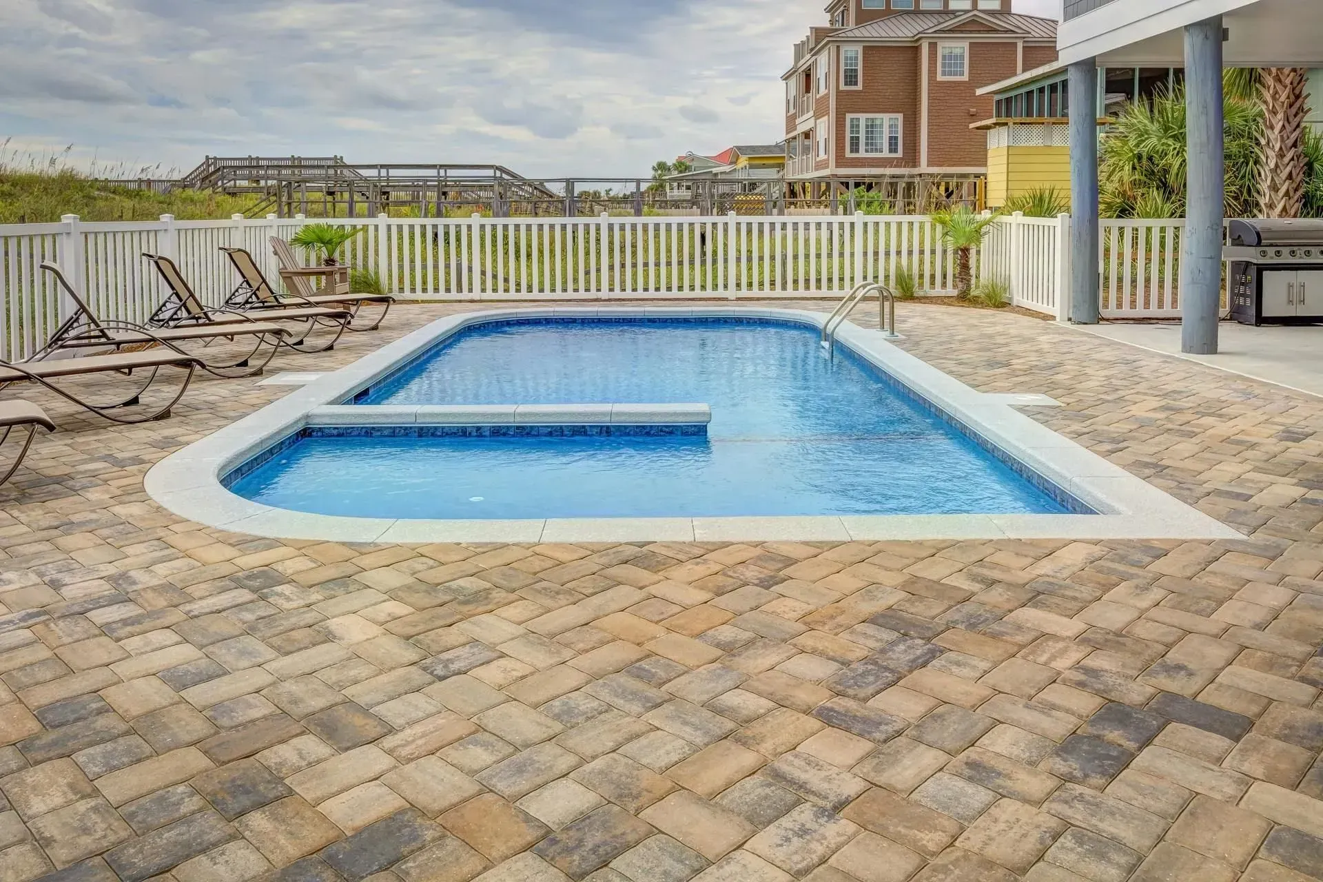 Swimming pool with a patio and beach view.