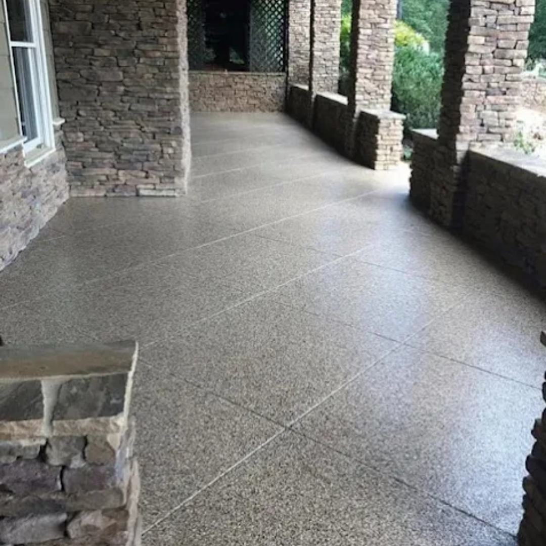 A covered porch with a speckled gray floor and stone columns.