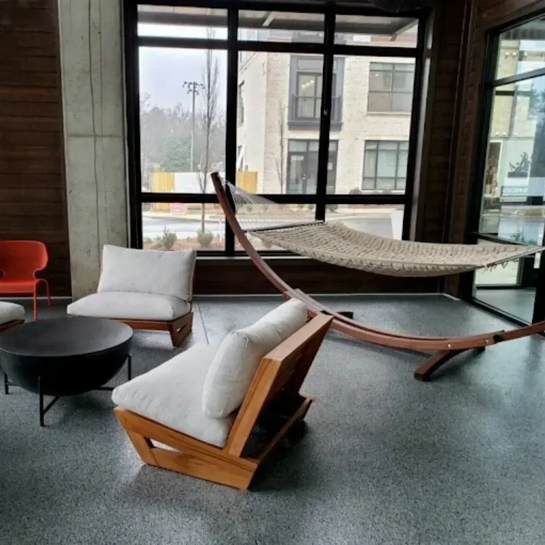 Indoor lounge area with hammock, white cushioned chairs, and a black coffee table.
