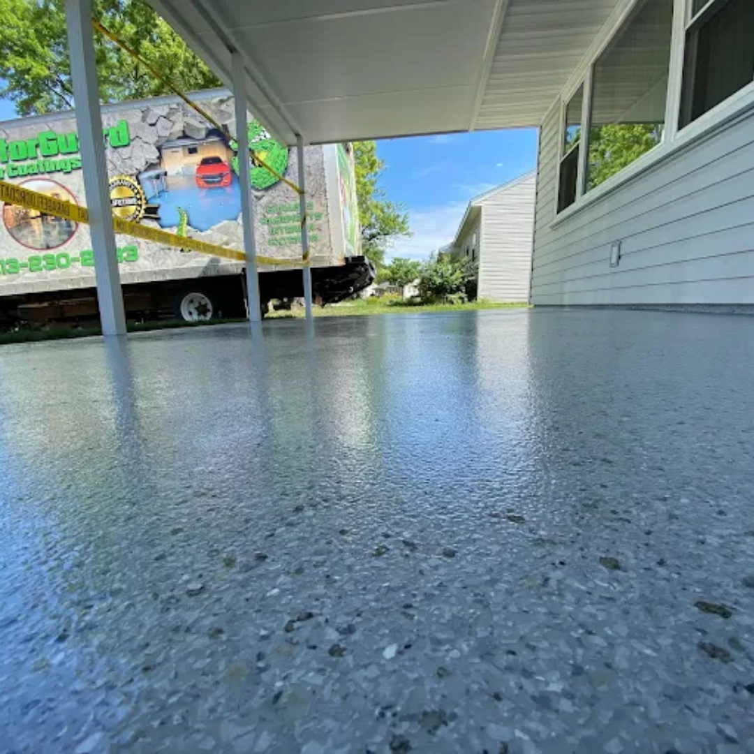 Gray, glossy concrete patio under a white overhang. A work truck is in the background.