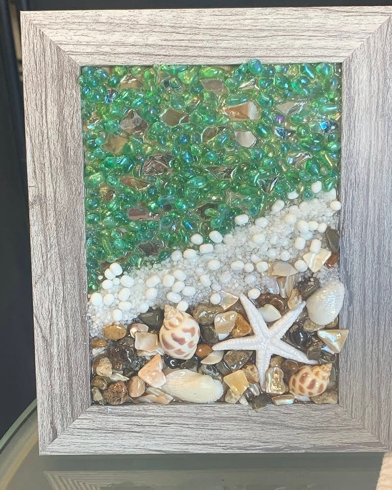 Framed seashell mosaic with green, white, and tan pebbles and a starfish centerpiece