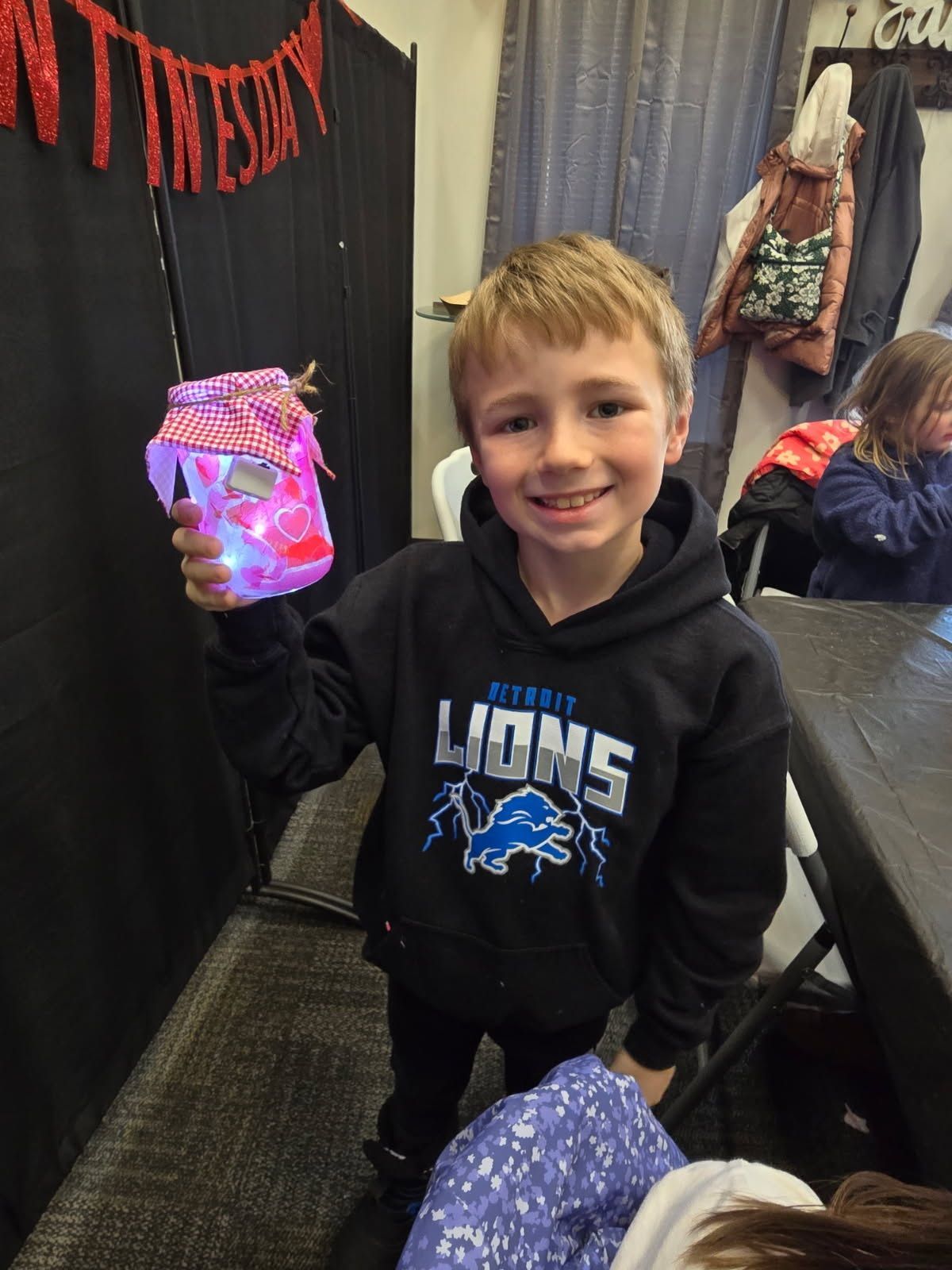 Smiling child holding a glowing pink toy in a decorated indoor room