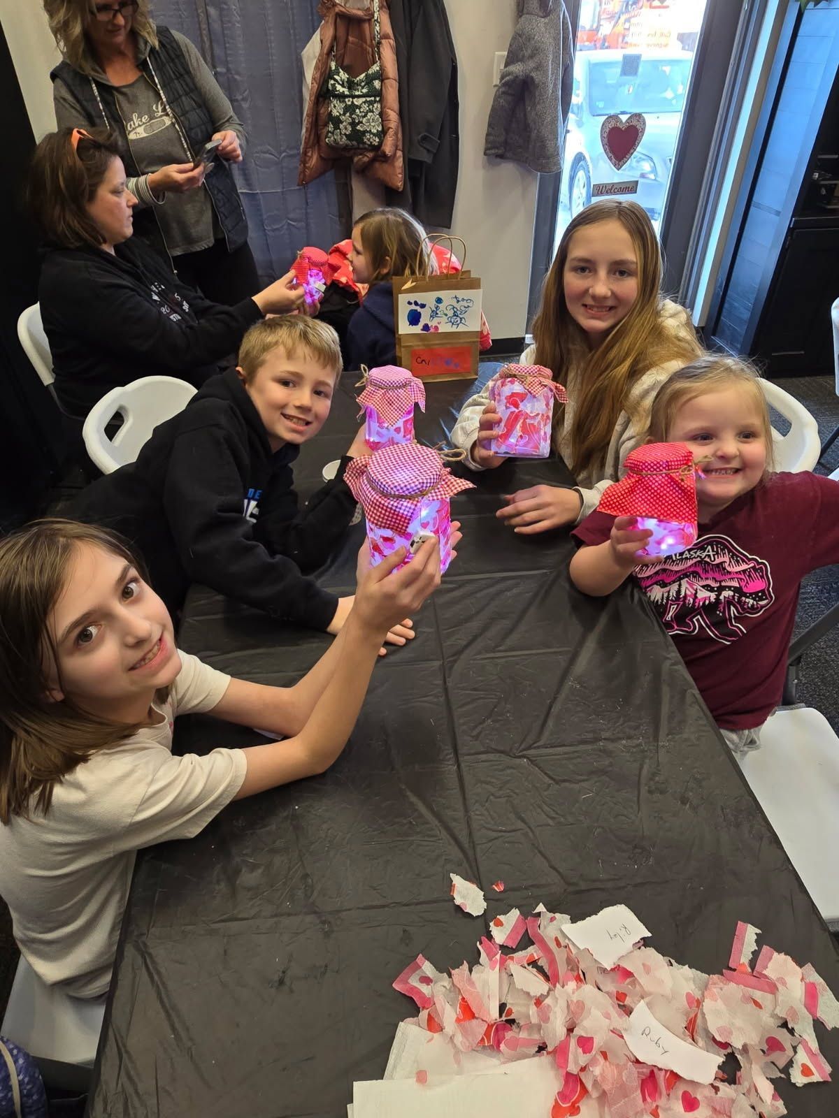 People seated around a table, smiling and holding pink gift bags at a party booth