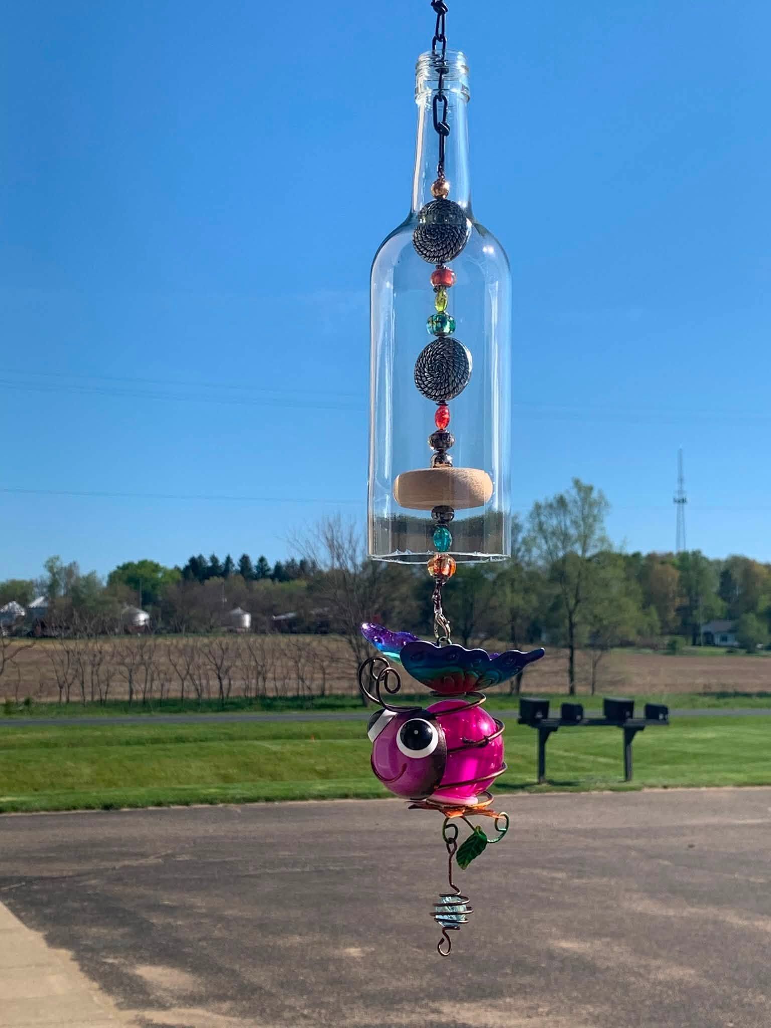 Colorful hanging glass sculpture outdoors on a sunny lawn under a blue sky