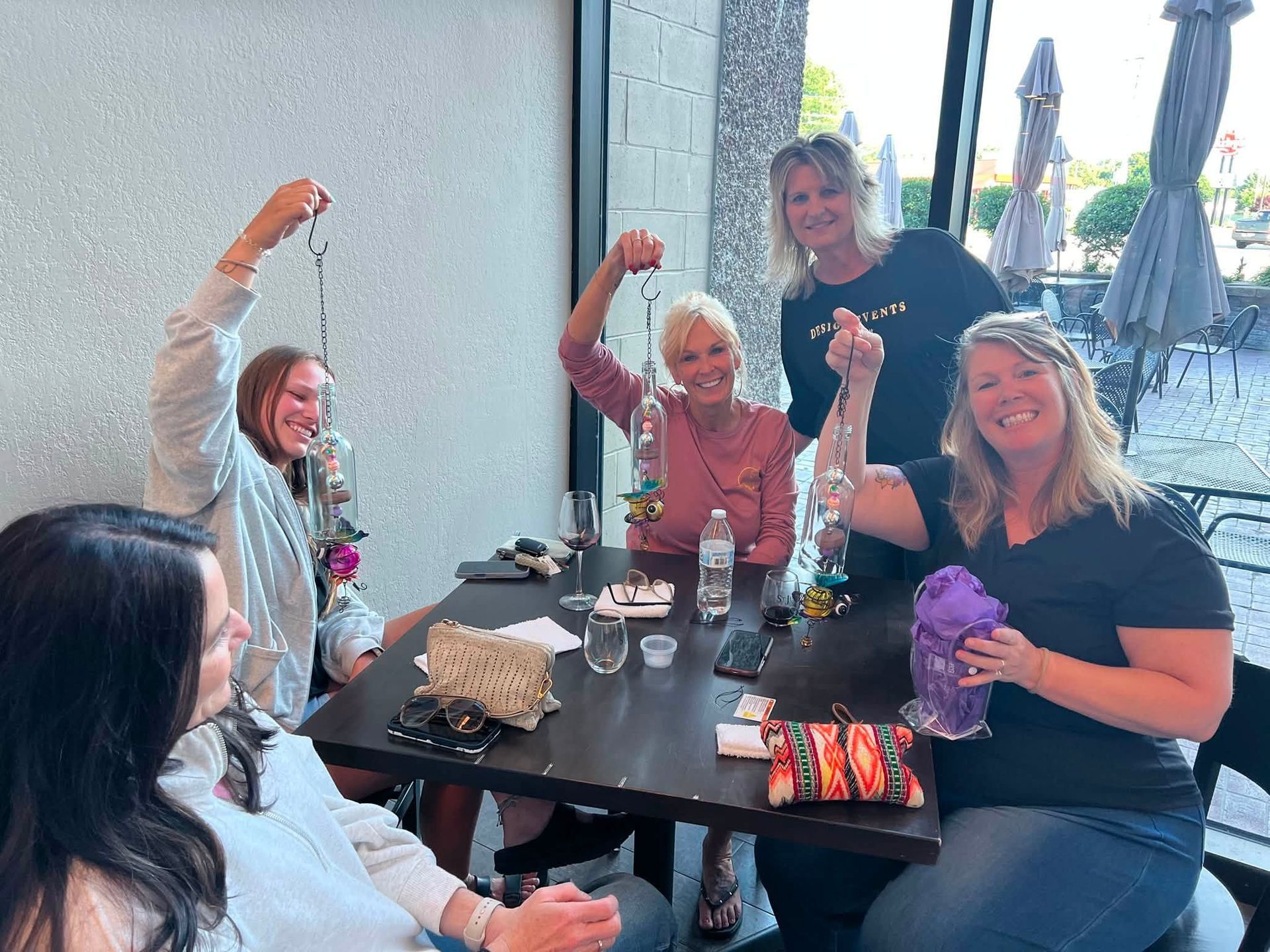 People raising drinks and cheering at a restaurant table with food, drinks, and umbrellas in the background