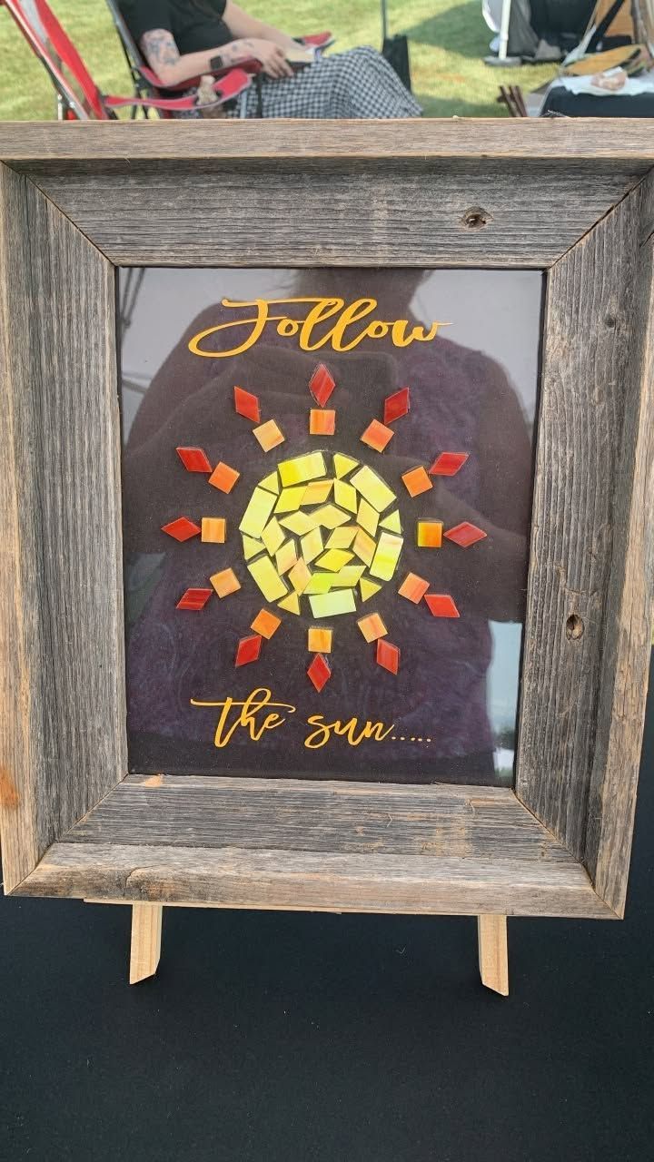 Framed mosaic art on an easel reading “Follow the sun” in yellow and orange