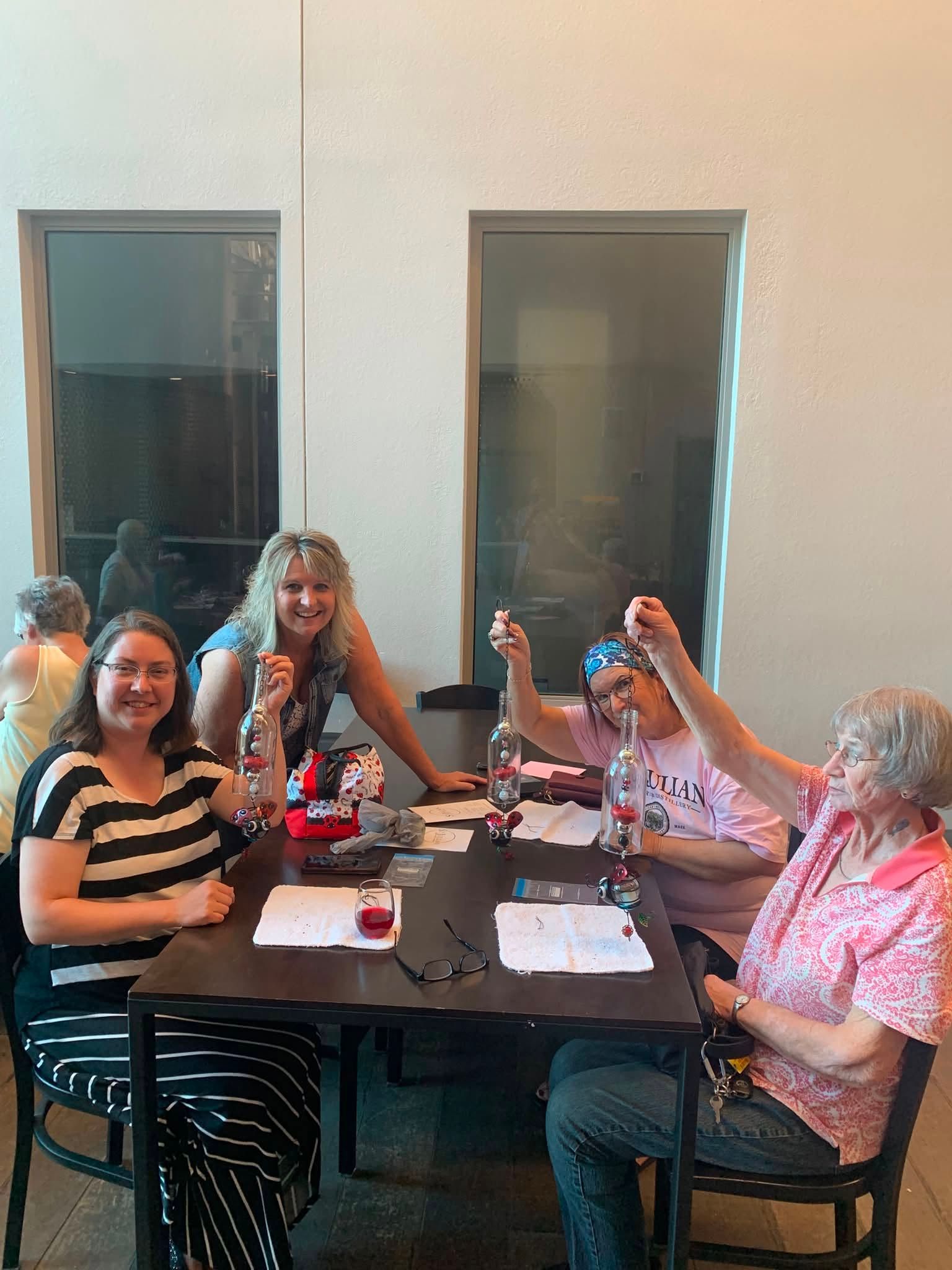 Five people seated at a table indoors, smiling and posing with raised drinks in a casual gathering.