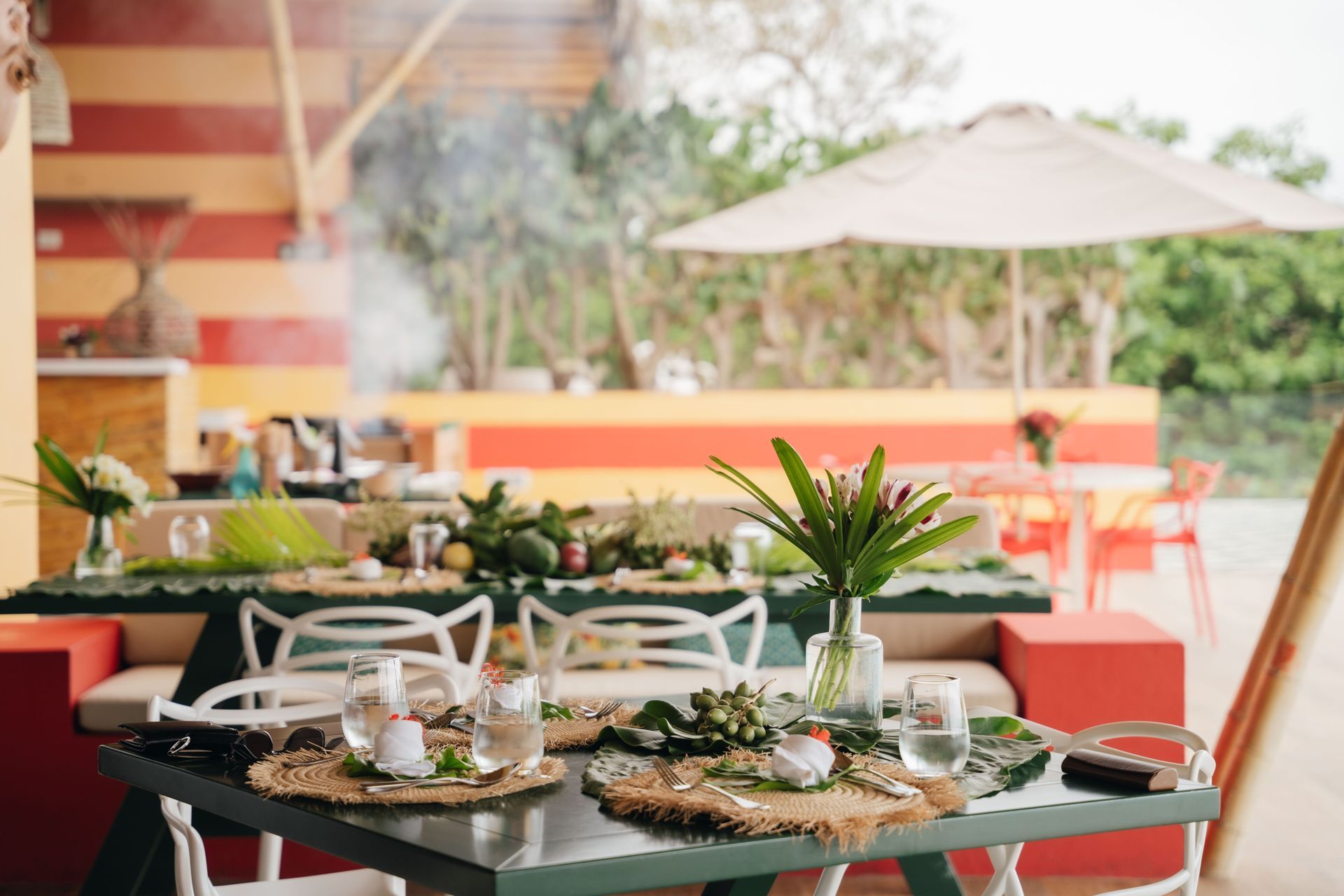 Outdoor dining table set with glasses, greenery, and tropical decor.
